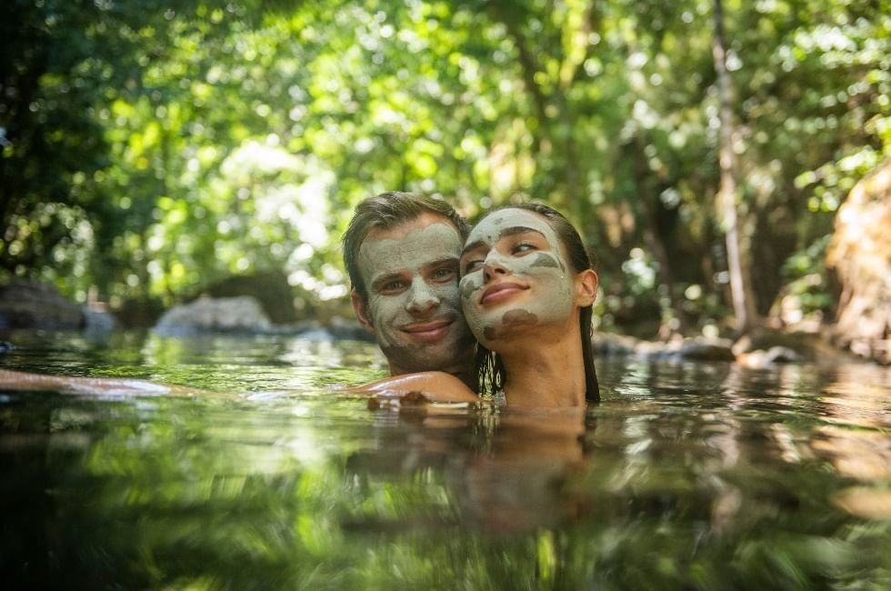 A couple relaxing in the river with volcanic mud masks, Rio Perdido, Costa Rica
